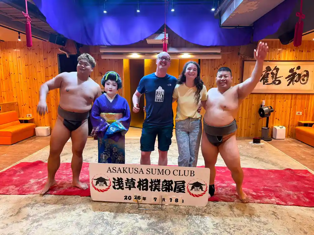 Group of sumo wrestlers and visitors with club banner