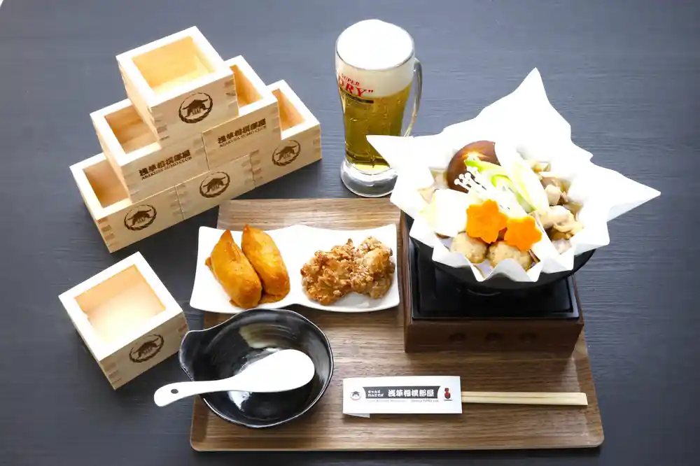Japanese meal with beer, wooden boxes, and various dishes