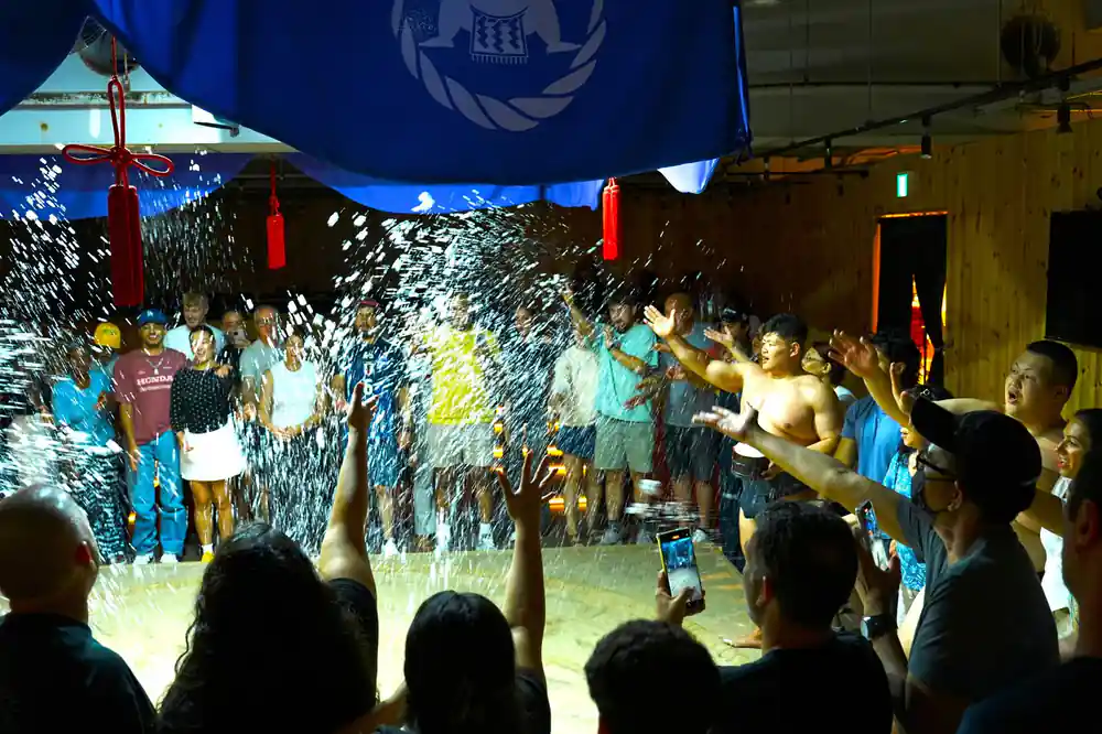 Large crowd watching sumo match with water effects