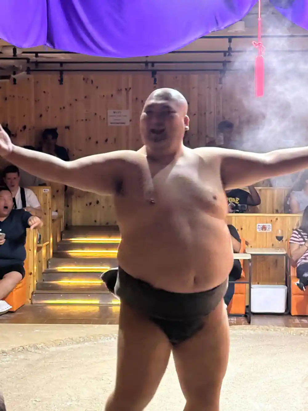 Sumo wrestler in sumo pose on arena floor indoors