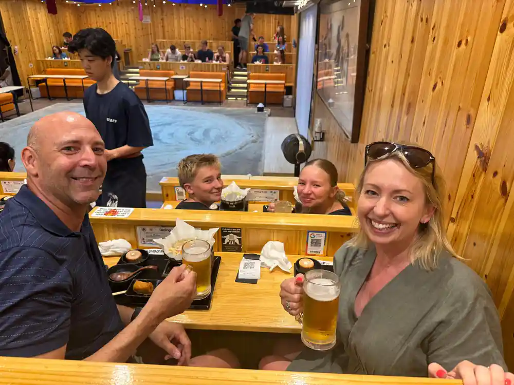 Family of four at wooden table with food and drinks