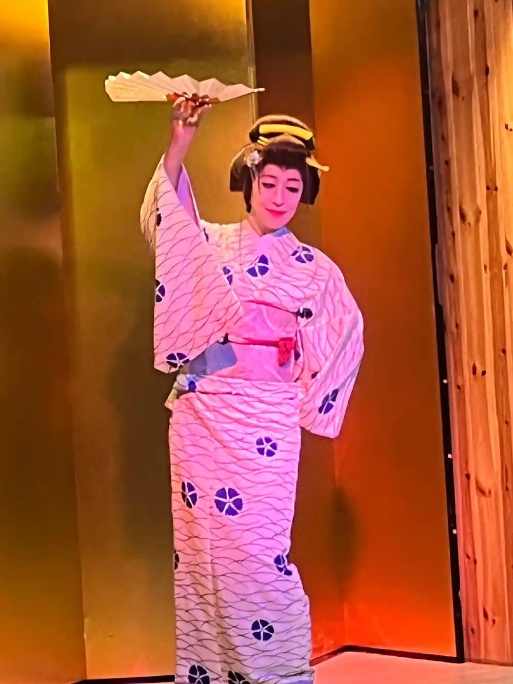 Person in patterned kimono with fan on illuminated stage
