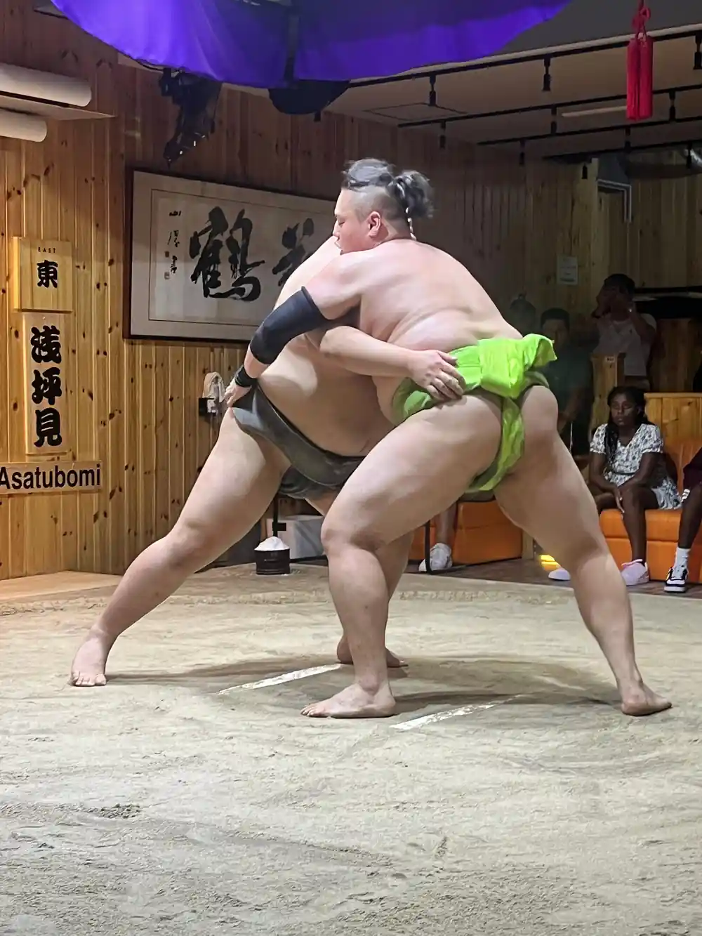 Two sumo wrestlers in match on sand arena indoors