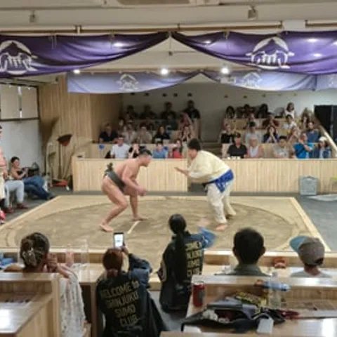 Two wrestlers facing off in the ring at a Tokyo sumo show