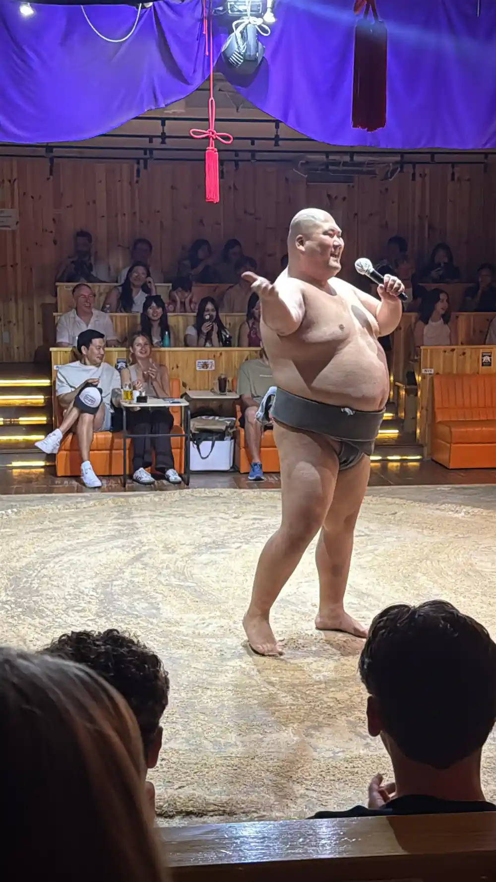 Sumo wrestler speaking into microphone at indoor event