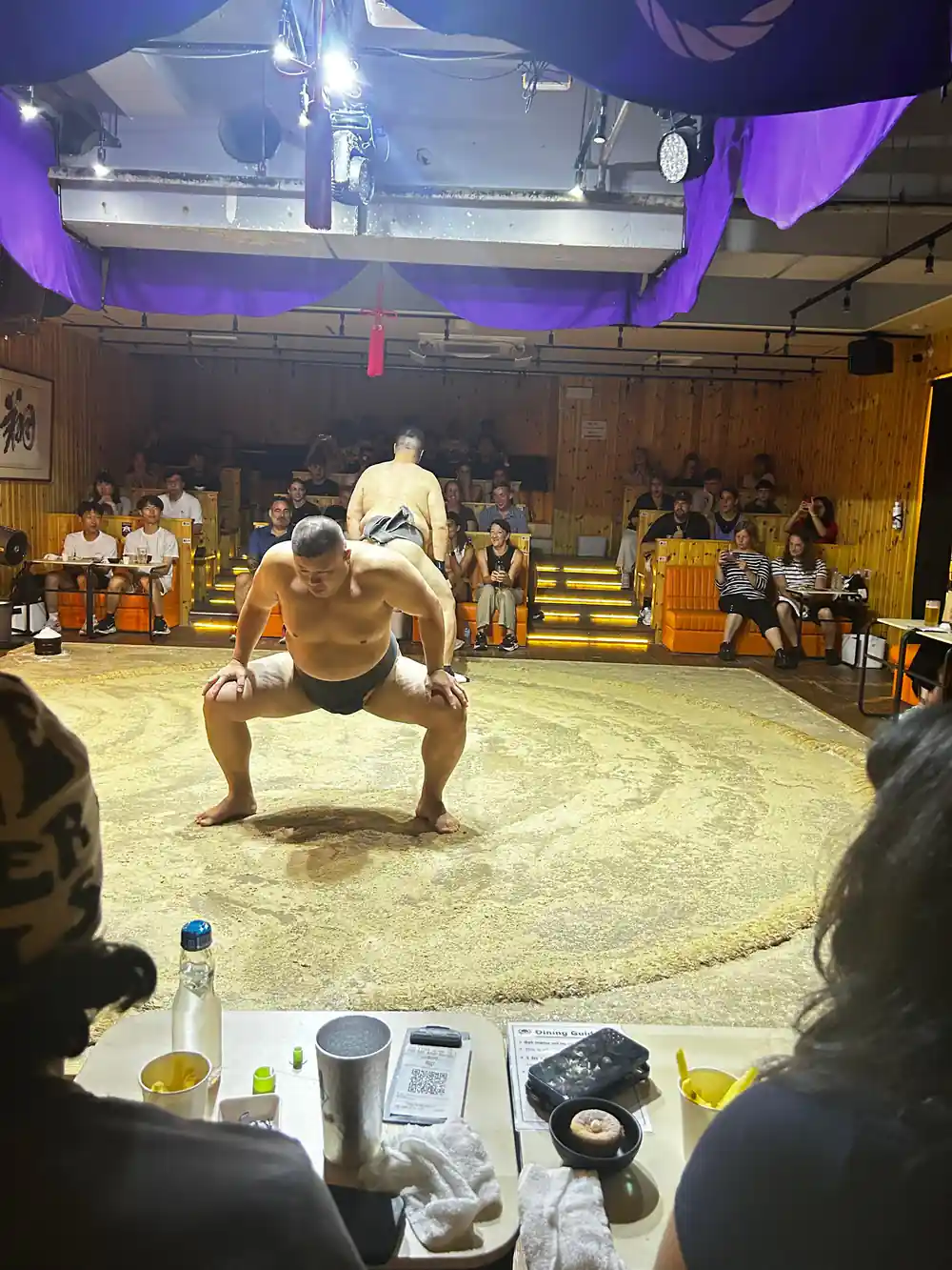 Sumo wrestler in squat stance on sand ring floor