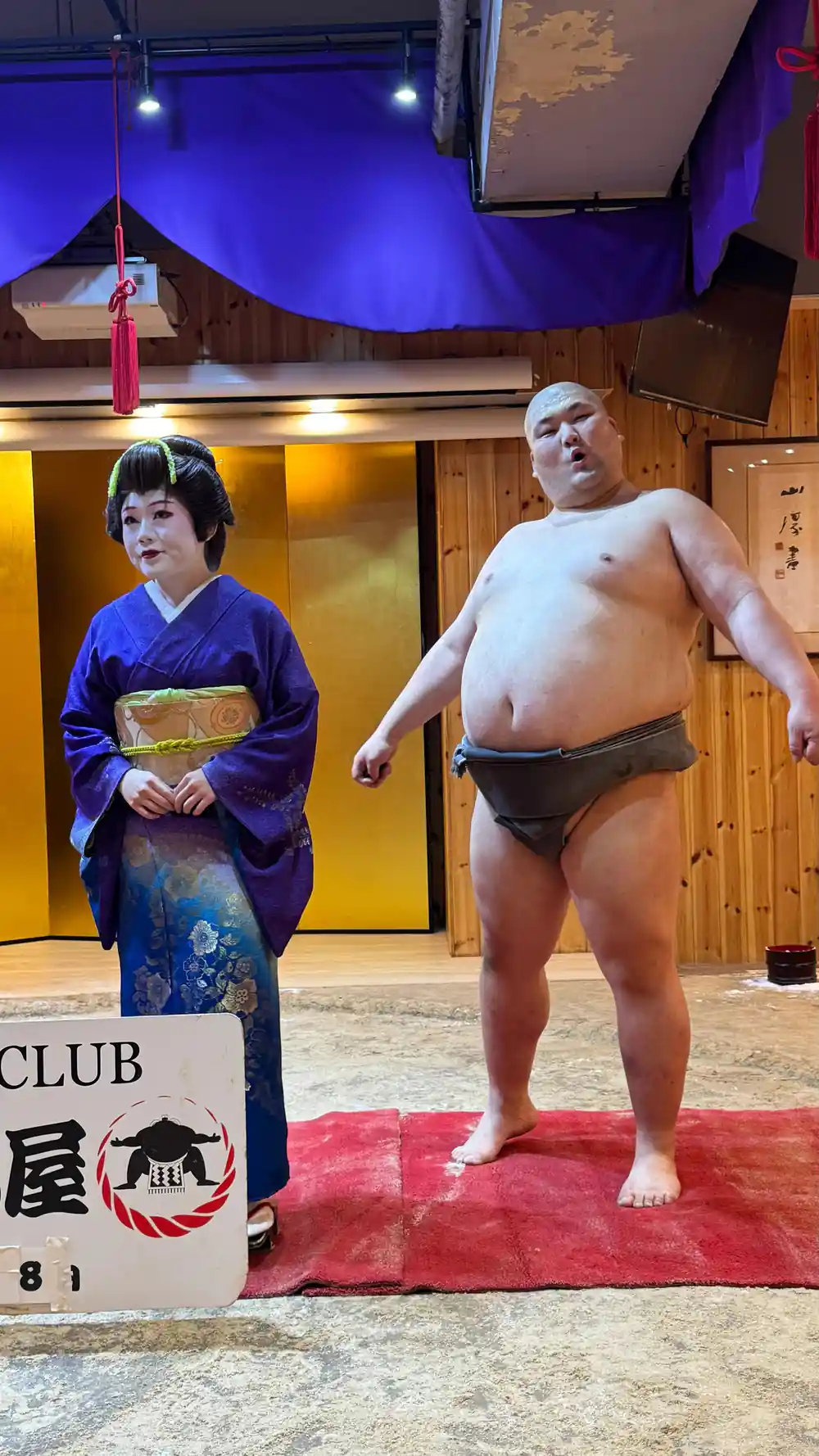 Sumo wrestler and woman in kimono at sumo club