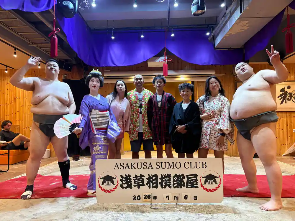 Sumo wrestlers posing with visitors at club entrance