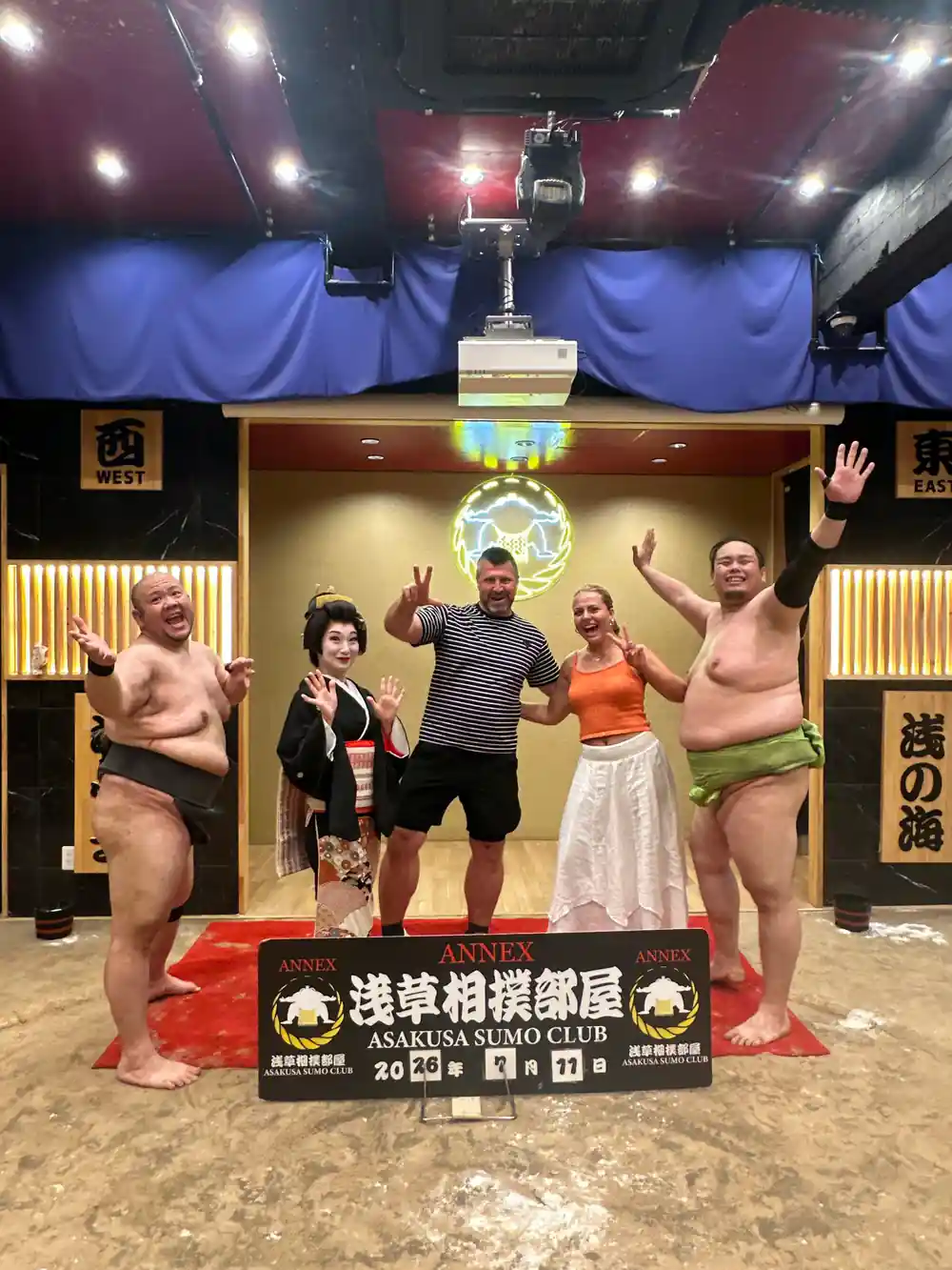 Sumo wrestlers and visitors posing on platform stage