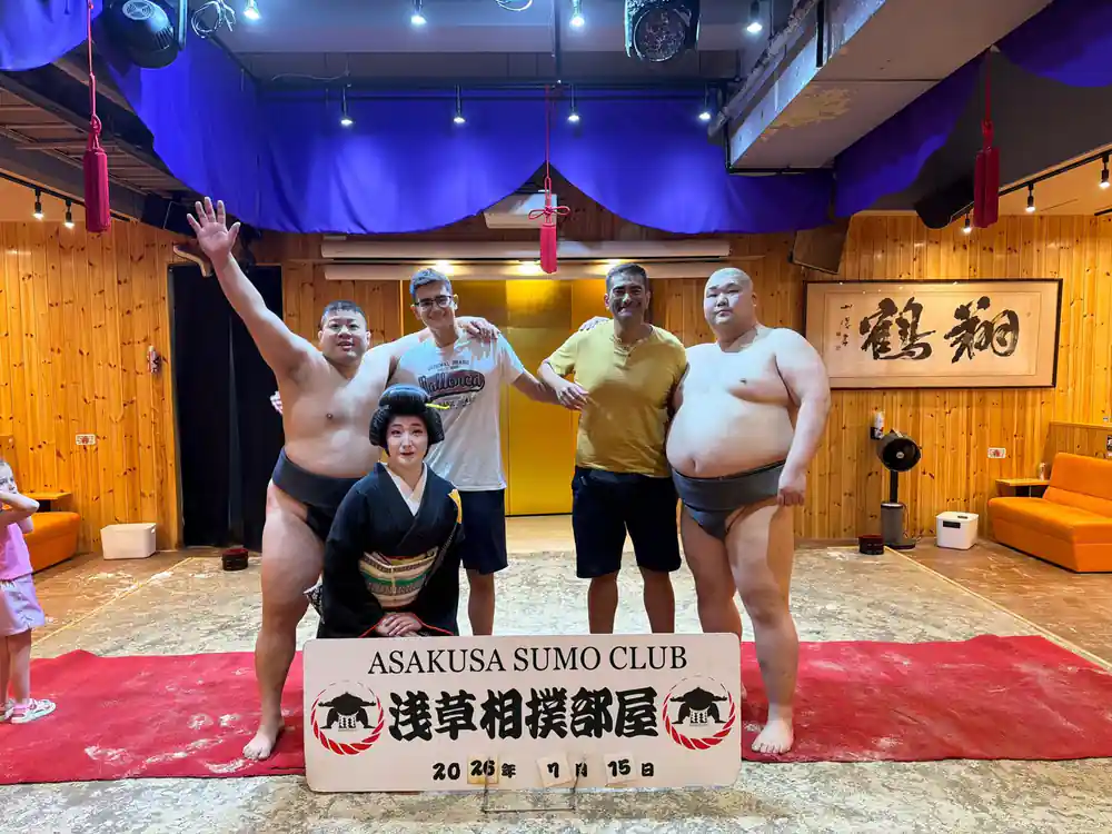 Three sumo wrestlers posing with woman at sumo club