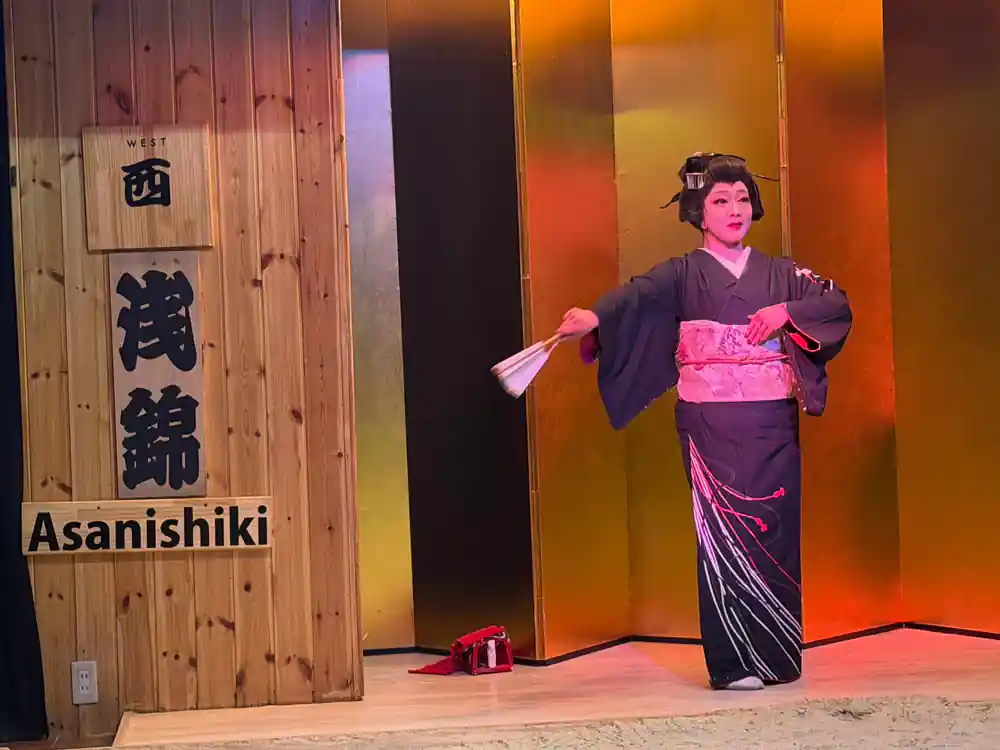 Woman in purple kimono with pink belt performing fan dance