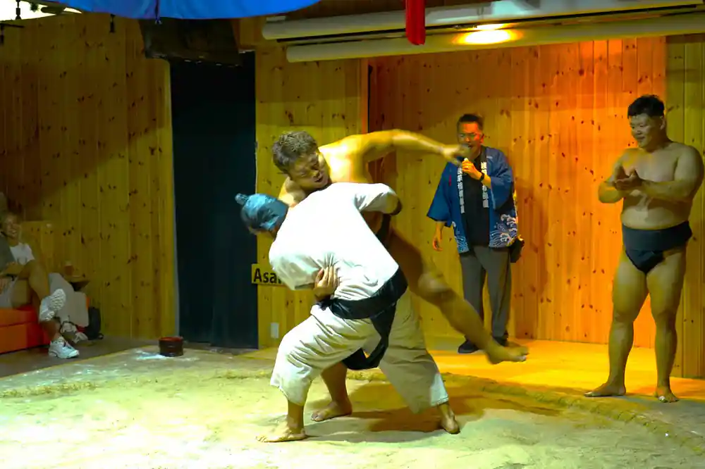 Young sumo wrestler doing backflip in training ring